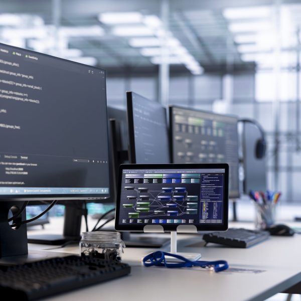 Computers in data center hosting rackmount ensuring faultless operations conditions. Close up of PC monitors and tablet on desk used for monitoring data center devices energy consumption